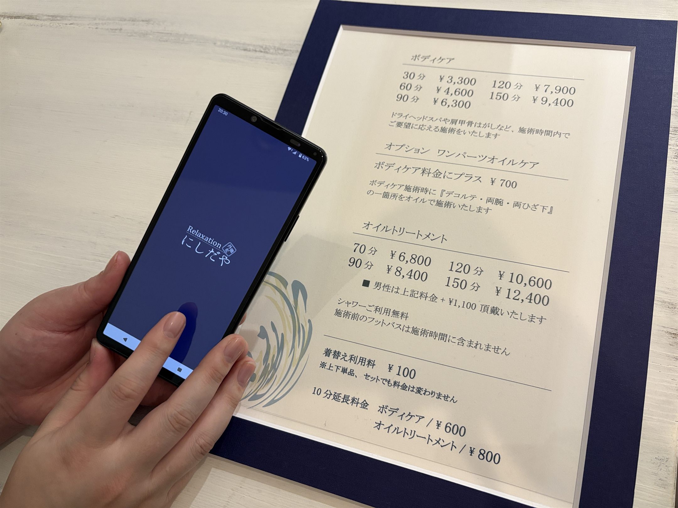 スマートフォンでオンライン予約画面を開くお客様とコースメニュー表